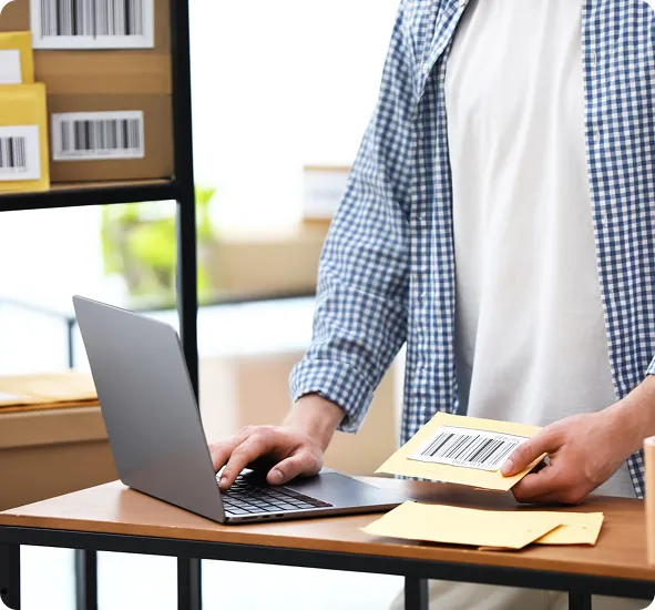 Online shop owner surrounded by parcels and stock, working through order admin by hand