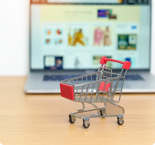 Shopping trolley in front of a laptop showing an online store being outgrown